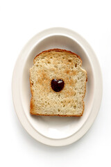 Baked bread served on an oval plate, decorated with a heart of strawberry jam in the center.isolated on a white background.