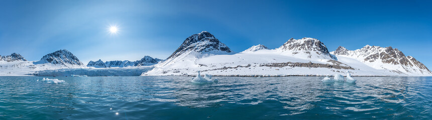 Spitzbergen, Svalbard, Norwegen: Arktische Gebirgslandschaft spiegelt sich im stillen Wasser des Magdalenefjorden mit Treibeis unter strahlend blauem Himmel. © stylefoto24