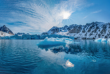 Spitzbergen, Svalbard, Norwegen: Arktische Gebirgslandschaft spiegelt sich im stillen Wasser des Magdalenefjorden mit Treibeis unter strahlend blauem Himmel. © stylefoto24