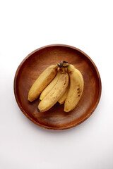 Bananas on a wooden round plate. White background.