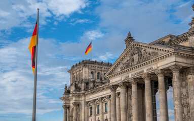 Berlin, germany, august 12, 2023. Reichstag building  with german flags flying above its historic facade under a bright blue sky, symbol of democracy