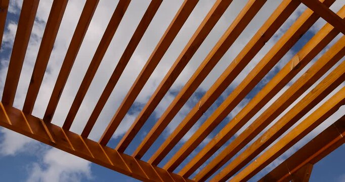 a wooden frame made of logs on the beach in sunny weather against a blue sky with clouds, part of a wooden frame building under construction on the beach