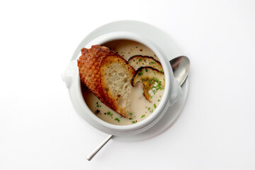 A bowl of warm mushroom soup, served with bread. White background.