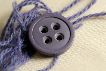 Beautiful purple button with yarn on soft fabric background
