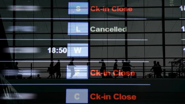 Flights delayed and canceled on departure board, flight delay footage. Device screen with airport flight information.