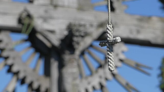 Small rope cross hanging in front of wooden crucifix
