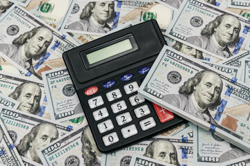 Fototapeta premium Calculator and stack of one hundred dollar bills. Accounting, finance and business concept.