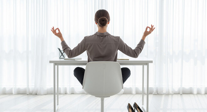 Businesswoman meditating in office chair, rear view of zen employee doing yoga at desk