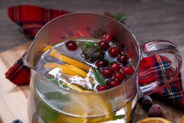 Close-Up of Glass Pitcher with Orange Slices, Mint, and Cranberries in Hot Water, Refreshing Beverage