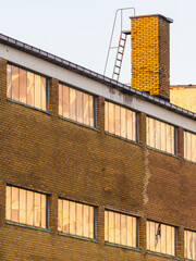 Abandoned old industry building in Gothenburg with empty windows and rusty chimney during sunset hours