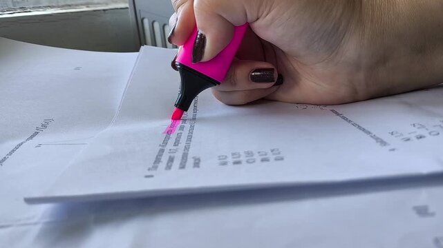 A woman's hand underlines the text on the paper with a pink marker. Synopsis, study. Documents, contract
