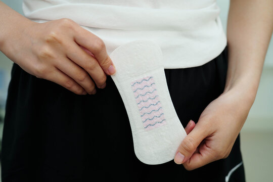 Asian woman holding sanitary napkin pad for hygiene menstrual period cycle protection.
