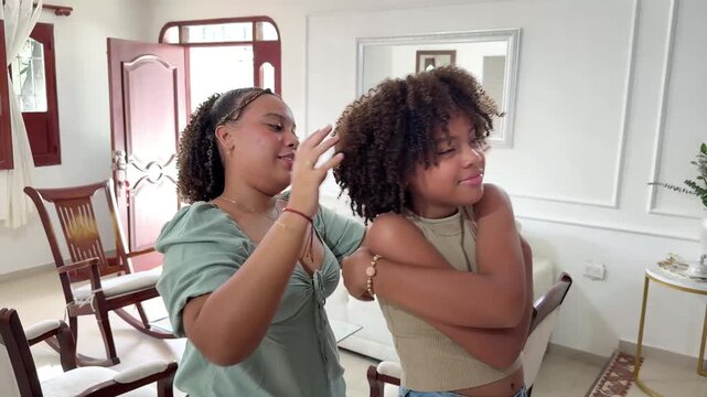 Young woman styling her sister's natural curly hair, sharing beauty knowledge and family traditions