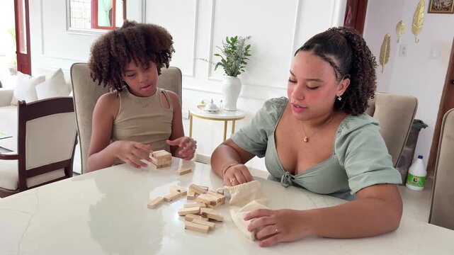 Big sister plays a fun game with wooden blocks with her little sister, enjoying family time at home