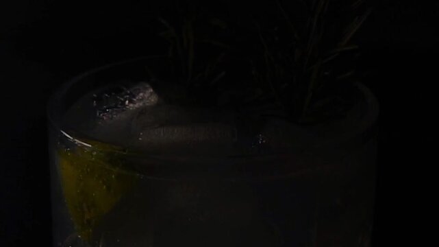 Delicious alcoholic cocktail made with jin tonic and ice in glasses for relaxing at night and refreshing in the summer. Spices and green lime for flavor. Bartender and bar. Rosemary burns with fire