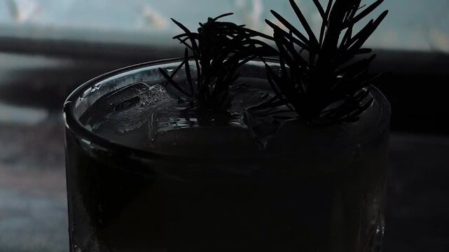 Delicious alcoholic cocktail made with jin tonic and ice in glasses for relaxing at night and refreshing in the summer. Spices and green lime for flavor. Bartender and bar. Rosemary burns with fire