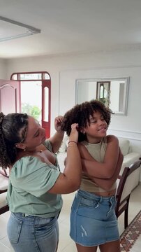 A loving older sister combs her little sister's afro hair, passing on family knowledge and traditions