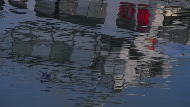 Abstract reflection of a white boat on calm blue sea water, rippling liquid texture, artistic nautical background.