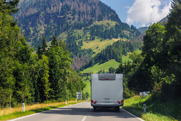 Scenic back view modern white family rv camper van vehicle drive Europe curvy road alpine pass mountain sunny summer day. Rving motorhome lifestyle travel adventure tourism trip Alps journey concept © Kyryl Gorlov