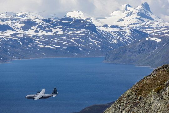 Military Transport Aircraft over Norwegian Mountain Lake in Jotunheimen National Park.