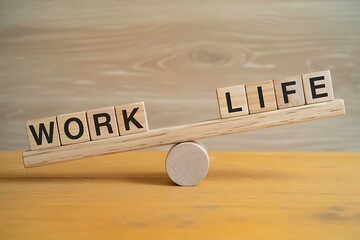 Wooden seesaw with blocks spelling work and life in balance on yellow surface