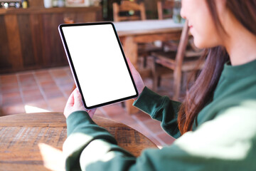 Mockup image of a woman holding digital tablet with blank white desktop screen in cafe