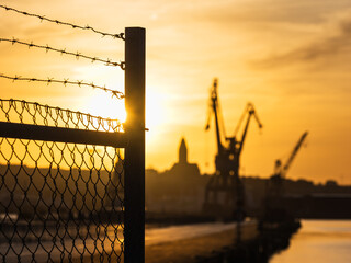 Fence in Gothenburg at sunset with cranes seen in the background