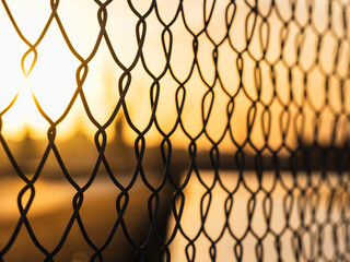 Fence at sunset in Gothenburg showing a wire pattern with a warm glow in the background