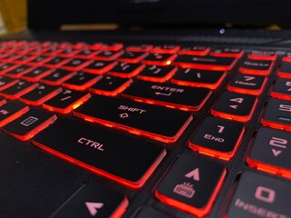 Close-up of a modern computer keyboard with orange LED backlight, futuristic technology concept, low light environment, selective focus.