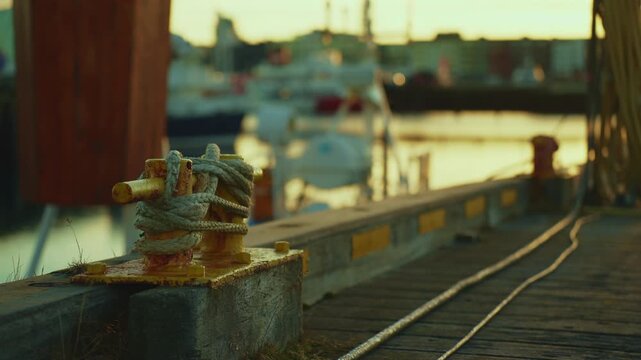 Close-up of a harbor bollard with mooring ropes and blurred sea movement in the background, 4K.