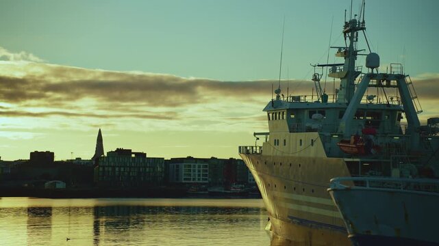 Large ship at the harbor with the city skyline and Hallgrimskirkja silhouette at golden sunrise, 4K.