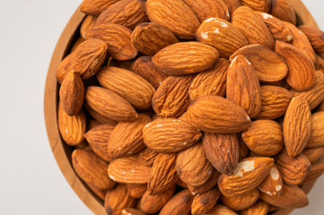Fototapeta premium Close-up of almonds in a wooden bowl on gray background. Delicious organic nuts top view. Concept of dietetics and healthy eating. Almond texture