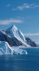 Towering Iceberg Rising from Icy Waters Under Clear Blue Sky in Serene Landscape