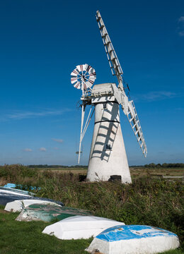 Thurne Dyke Drainage Windmill on The Norfolk Broads National Park, with old upturned rowing boats, Thurne,  Norfolk, England, UK
