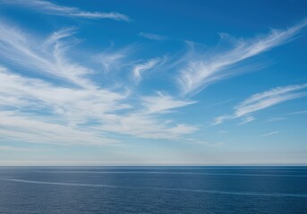 Obraz premium A wide open blue expanse stretching over a tranquil bay, featuring high cirrus clouds and a subtle gradient of coastal atmosphere above the horizon line ,bright ,coast ,bay