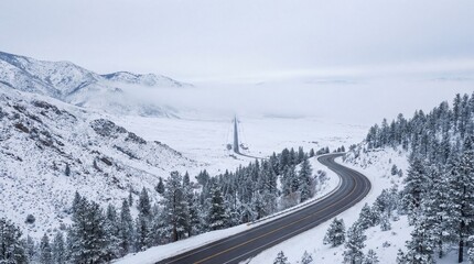 Winding mountain highway curves through snowy evergreen forest landscape in winter