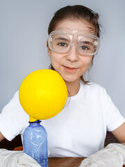 A girl conducts a funny science experiment with a yellow balloon on a bottle.
