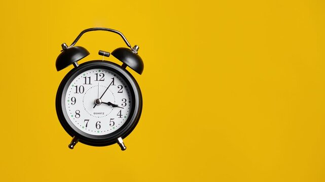Vintage alarm clock with copy space. Clock face on yellow background. Time lapse. Time running fast. Analog clock. Table clock show running time. Close up in 4K, UHD