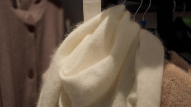 Soft fluffy cream mohair scarf hanging on a hanger. Clothing accessories concept.