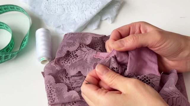 A woman carefully unpicks a seam on lace fabric with ripper.