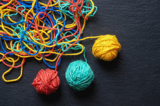 Untangling tangled threads as concept of problem solution. Colorful tangled threads and balls of wool on black background. Copy space
