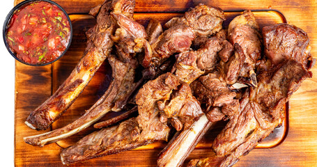 Grilled lamb chops served with salsa on a wooden board for a tasty meal experience