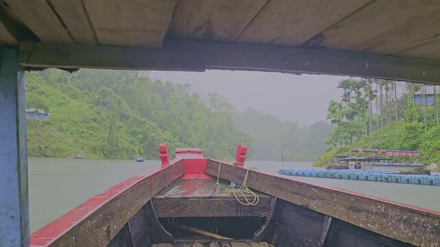 POV boat ride on Dumboor Lake during heavy rain. Moving towards Nariyal Kunja island with lush green hills and misty water in Tripura. Monsoon travel footage.