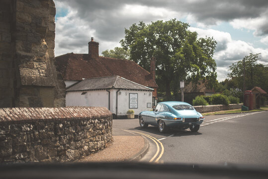 Classic blue sports car coupe driving on a country road