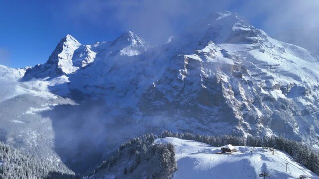 Drone video of M&auml;nnlichen in winter, featuring snow-covered ski slopes, alpine terrain, and scenic mountain views in Switzerland.