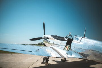 Vintage silver airplane parked on the tarmac on a bright, sunny day © Pavel Babic