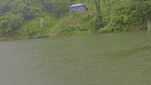 POV boat ride on Dumboor Lake during heavy rain. Moving towards Nariyal Kunja island with lush green hills and misty water in Tripura. Monsoon travel footage.