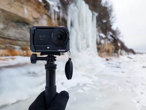 PALDISKI, ESTONIA - FEBRUARY 8, 2026: A DJI Osmo Action 6 camera with Telesin accessories captures frozen Pakri cliffs in winter.