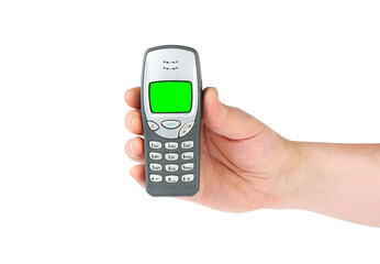 Hand holding old push-button mobile phone with green screen on isolated white background.