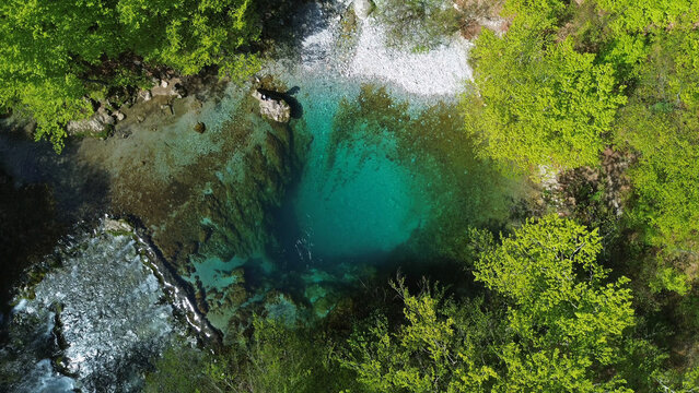 Turquoise spring water surrounded by lush green forest